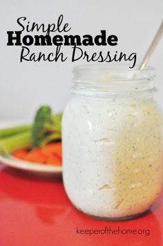 a jar filled with ranch dressing sitting on top of a red table next to vegetables