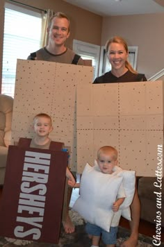 three people are holding cardboard boxes with the same name on them and one is holding a baby