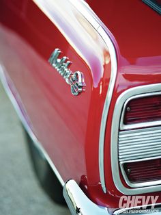 the front end of an old red car with chrome trim and emblems on it