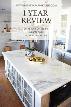 a kitchen island with white marble counter tops and cabinets in the background text reads 1 year review living with diy epoxy counters, my