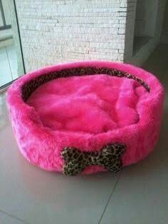 a pink dog bed with a bow on the front and bottom, is for sale