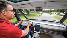 a man driving a car while holding an electronic device