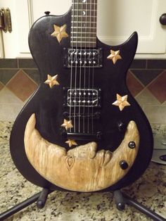 a black guitar with gold stars on it sitting on a counter next to a sink