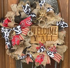 a welcome ya'all wreath is hanging on a door with burlocks and bandannas