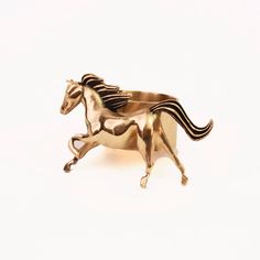 a gold horse brooch sitting on top of a white surface