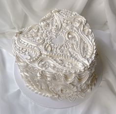 an intricately decorated white box sitting on top of a sheet covered tablecloths