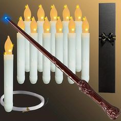 a harry potter wand is next to some white candles with blue lights on them and a black ribbon around it