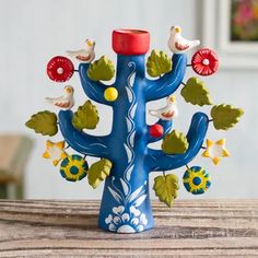 a blue vase with birds and flowers on it sitting on a table next to a wall