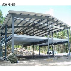 a large metal structure sitting on top of a dirt field next to a tree filled forest