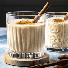 two glasses filled with dessert sitting on top of a table next to cinnamon sticks and cinnamon stick