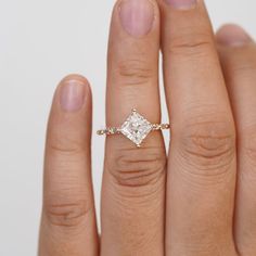 a woman's hand with a diamond ring on top of her finger, showing the center stone