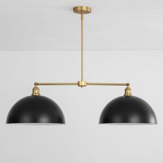 two black and gold pendant lights hanging from the ceiling in a room with white walls