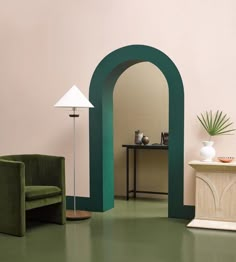 a living room with green furniture and an arch in the wall between two lamps on either side