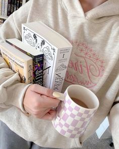 a person holding a coffee cup and some books