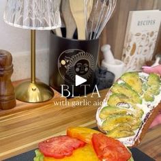 a sandwich with avocado and tomatoes on it sitting on a plate next to a lamp