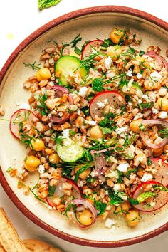 a bowl filled with vegetables and grains on top of a table next to crackers