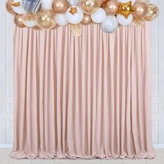 an arrangement of balloons and stars on a pink backdrop