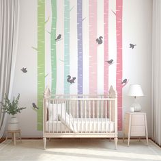 a baby's room with a crib and wall mural that has birds on it