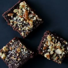 four brownies with nuts are on a black surface