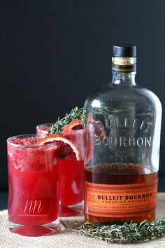 a bottle of bourbon next to a glass filled with red liquid