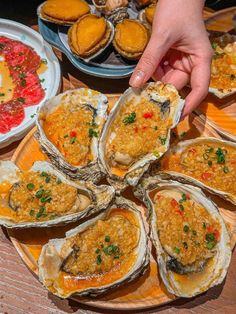 a person is picking up some oysters on a plate with other dishes in the background