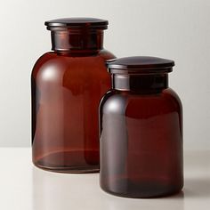 two brown glass jars sitting on top of a table