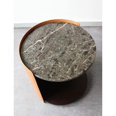 a marble top coffee table with wooden base and curved legs, on concrete flooring