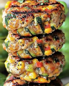 grilled chicken and vegetable patties stacked on top of each other with green beans in the background