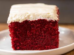 a slice of red velvet cake with white frosting sits on a plate, ready to be eaten