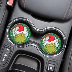 the grin face car coasters are on the center console of a car, with santa claus's hat