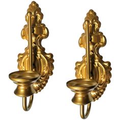 two golden wall sconces with handles and knobs on each side, one holding a candle