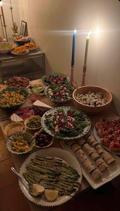 a table filled with lots of food on top of plates next to a lit candle