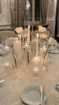 the table is set with white roses and candles for an elegant dinner or reception party