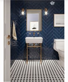 a bathroom with black and white tile, gold fixtures and a mirror above the sink