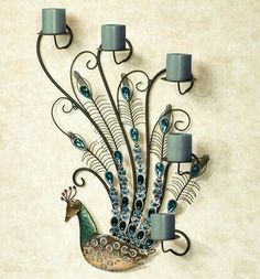 a metal peacock candle holder with tea lights on it's sides and a wall hanging in the shape of a peacock