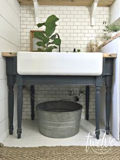 a bathroom sink with a plant on top of it next to a white brick wall