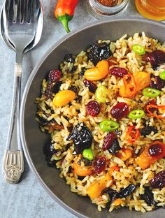 a bowl filled with rice and fruit next to silverware