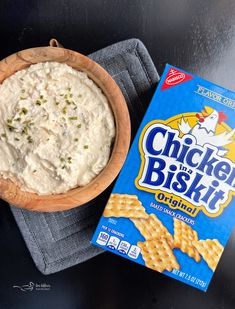 a bowl of chicken biscuit dip next to a box of crackers