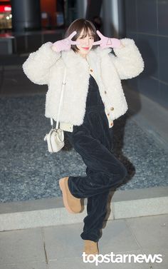 a woman is walking down the street with her hand on her head and wearing a fur coat