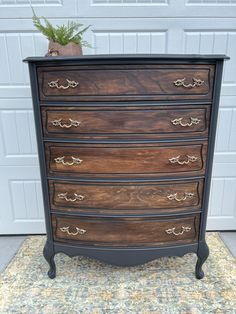 an old dresser is painted black and has gold hardware on the drawers, along with a potted plant