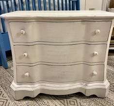 a white dresser sitting on top of a carpeted floor next to a blue crib