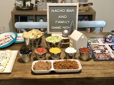 an assortment of food on a table with a sign that says nacho bar and family game night