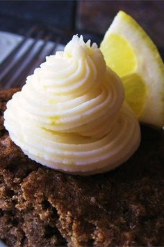 a piece of cake with whipped cream and a lemon wedge on top sits on a plate