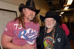 two men standing next to each other wearing cowboy hats