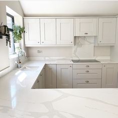 a kitchen with white cabinets and marble counter tops