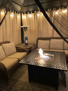 a living room with couches and a fire pit in the middle, surrounded by curtains