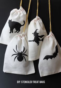 four halloween treat bags with black cat and spider silhouettes on them, hanging from twine strings