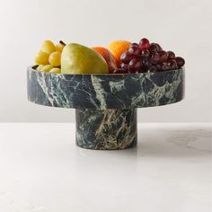 a marble bowl filled with fruit on top of a table