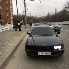 a black car parked on the side of a road next to a police officer and two men