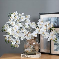 a vase filled with white flowers sitting on top of a table next to a book